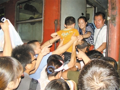 　　23日晚9时，野三坡火车站，众人帮助一带孩子的旅客上车。新京报记者 何光 摄