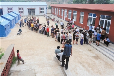 　　昨日，北车营村，安置点村民排队领取食物。新京报记者 尹亚飞 摄