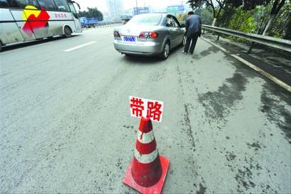 　　□在某高速公路上，一名带路人在锥形桶上放上招牌。