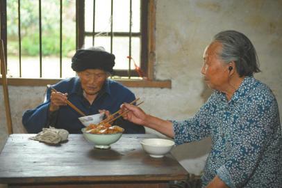 7月4日，家住成都双流太平镇前进村的老人付素清(左)和女儿吃饭，她一日三餐顿顿不离肉。