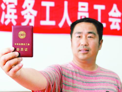 图为7月12日,来自湖北省孝感市的务工人员在展示中华全国总工会会员证