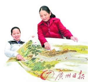 邓菊莲（左）在展示自己的作品。 