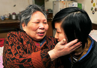 已经双目失明的黄桂英(左)看不清袁杰的长相了,抚摸袁杰的脸看她是否又瘦了