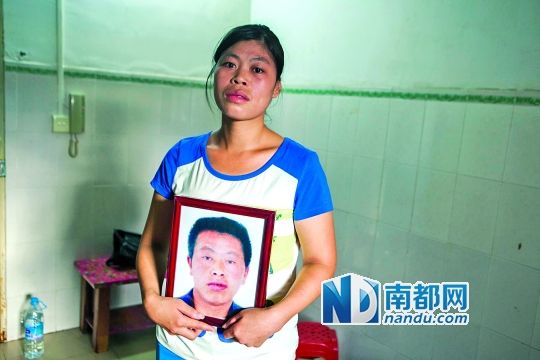 唐小姐抱着丈夫的遗像。她说老公没发病的时候是很爱她的。南都记者 王子荣 摄
