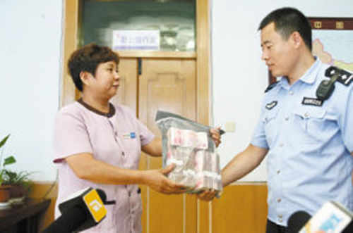 胡大姐将捡到的钱交给民警。资料图片