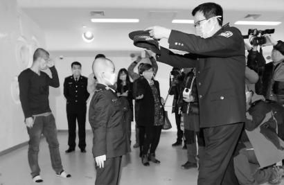 吉林市公安局党组成员、指挥中心指挥长付长坤（右）为刘梓曦戴警帽，看见儿子圆梦，刘晓冬偷偷地转过身去擦眼泪 