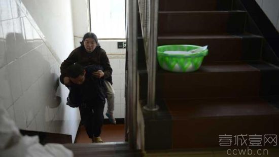 妈妈走不了路，儿子背她上楼。 春城晚报记者 翟剑 摄