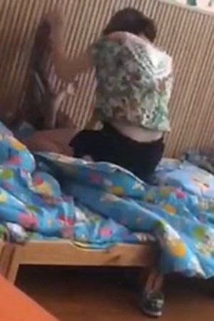 　女教师跨坐小孩身上，双手捆住小孩猛打。视频截图