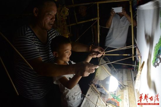 表演间隙，一位小朋友跟老朱学起了皮影。