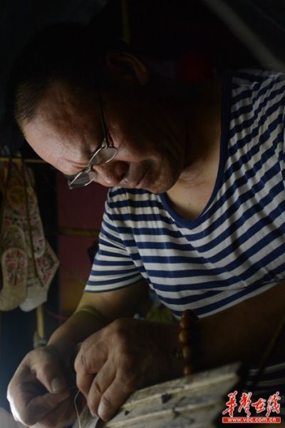 表演间隙，老朱抓紧时间修补破损的皮影道具。