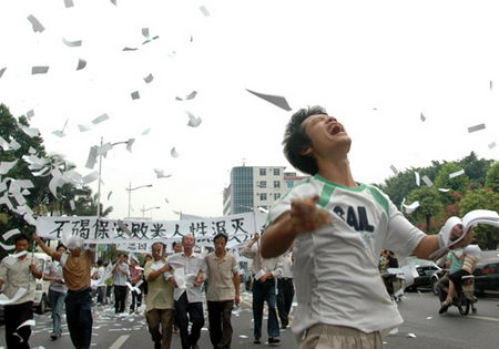 7月30日死者欧智锋的家属手持欧智锋遗像上街,并抛撒纸钱祭奠死者