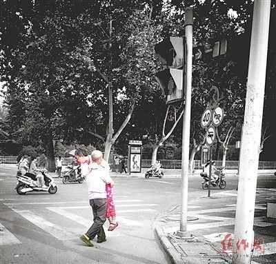 　　一位老人抱着行动不便的老伴在过马路。