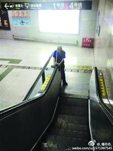 清洁工正用拖把擦拭自动扶梯的扶手　/@慢吞吞