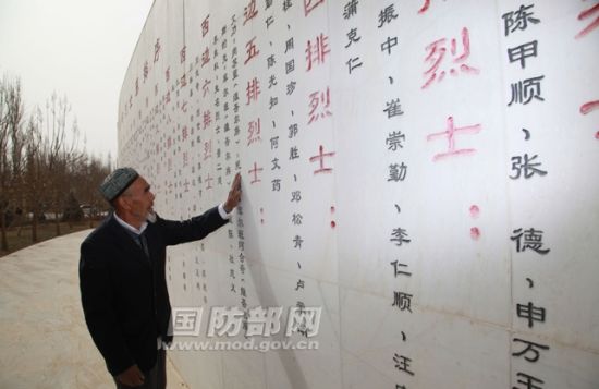 艾买尔•依提抚摸着陵园英烈墙上的烈士姓名，寄托着自己对战友的无尽思念。许必成摄