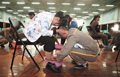 昨日，北京市未成年犯管教所，一名参加成人礼的服刑人员正在给母亲洗脚，母亲抱着孩子的头用自己的额头爱抚。