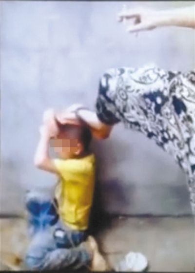 视频显示，该小学生遭到初中生暴力殴打。一初中生手持烟头，脚踩男童头部。 视频截图