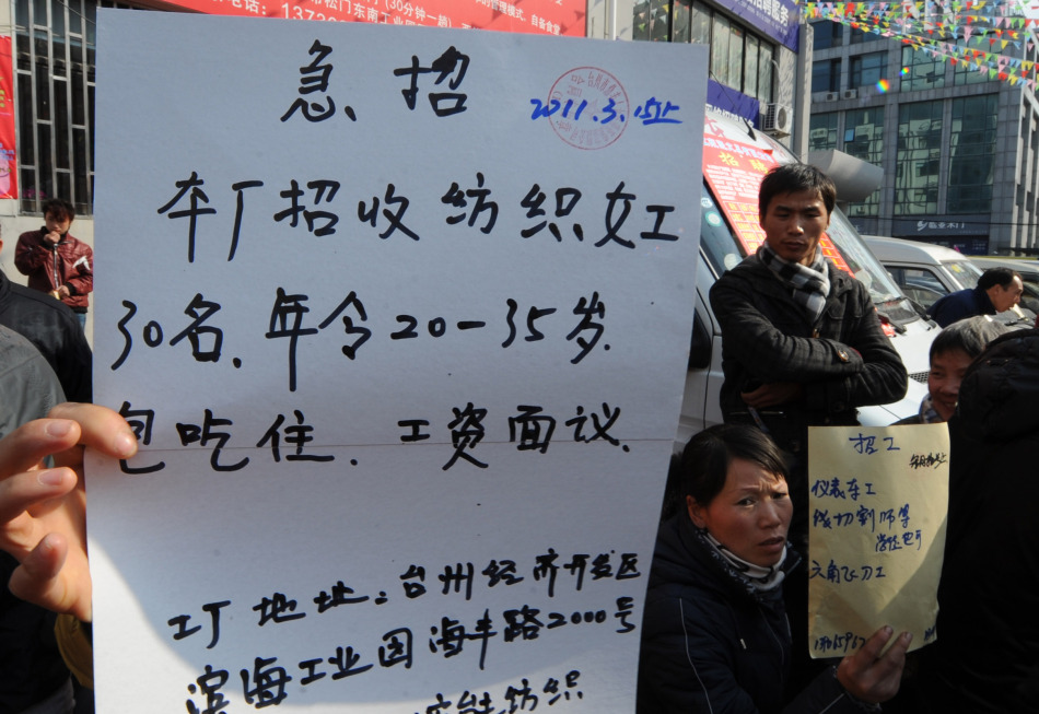 2月15日,浙江台州市路桥区劳动力市场外,招工者手举招工信息.