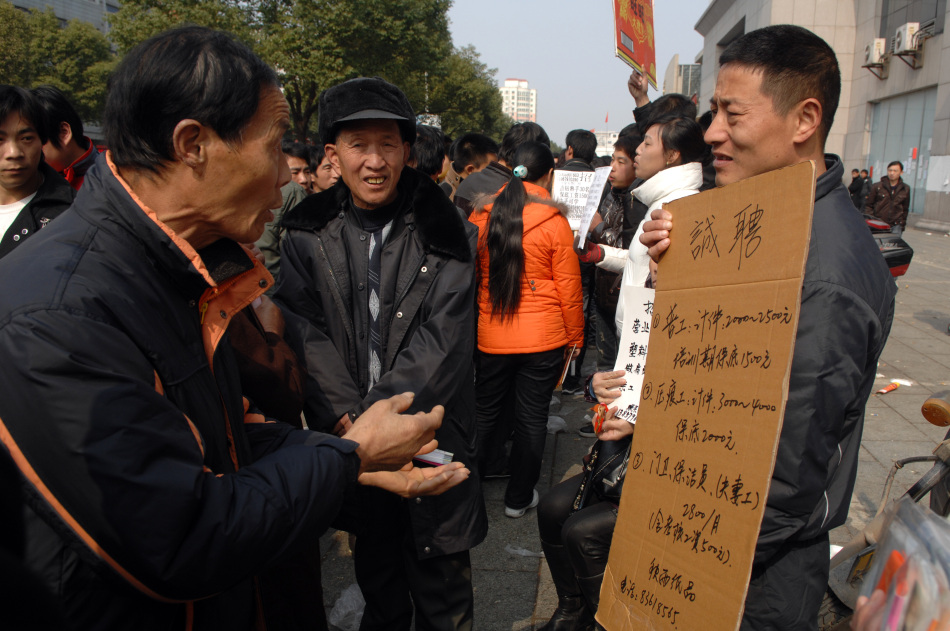 2月12日,在浙江义乌劳动力市场,一位应聘者(左)在和招聘者争论工资