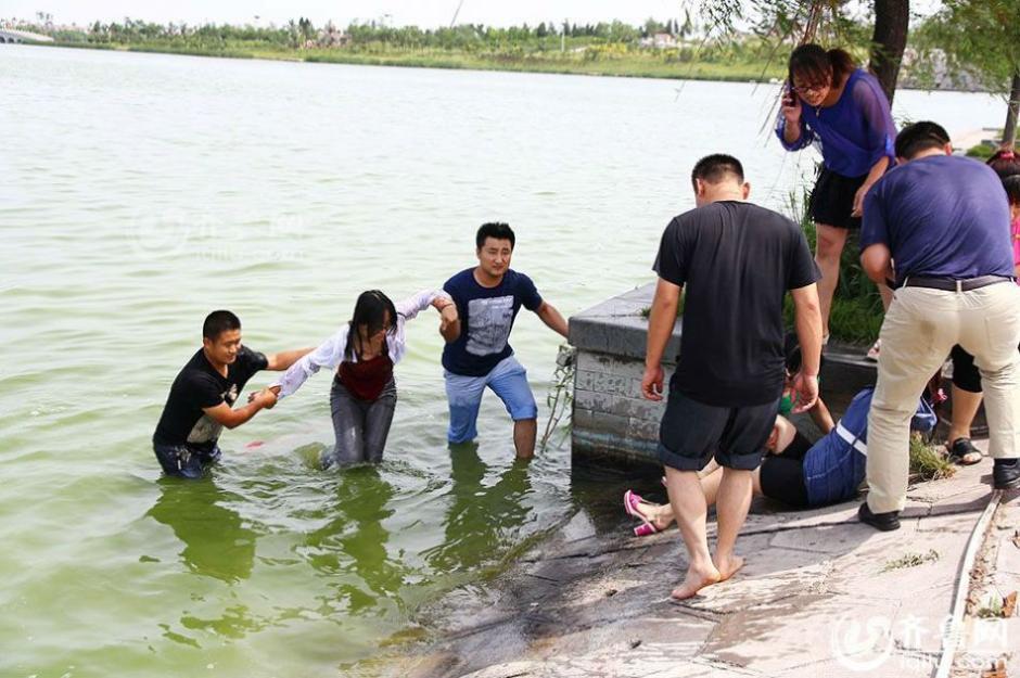 落水者被救起后,岸上的几位民众把救人女孩扶上岸.