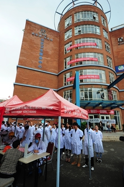 医生们无奈之下戴安全帽在医院前广场为患者看病.