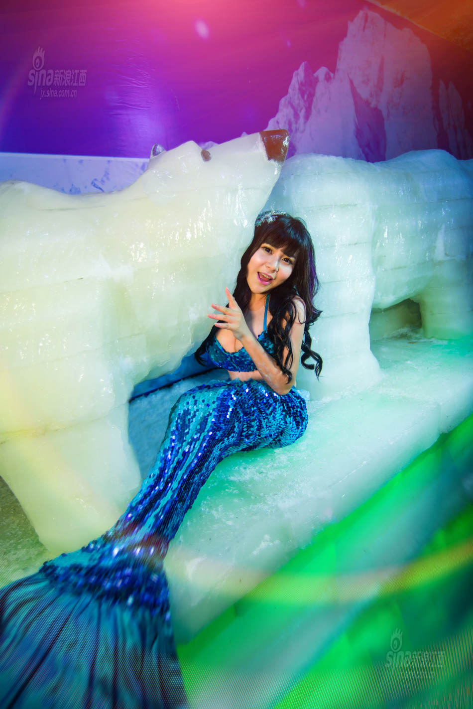 身着一袭蓝色的人鱼装,化身妩媚"美人鱼",和冰雕人物合影,演绎一幅幅