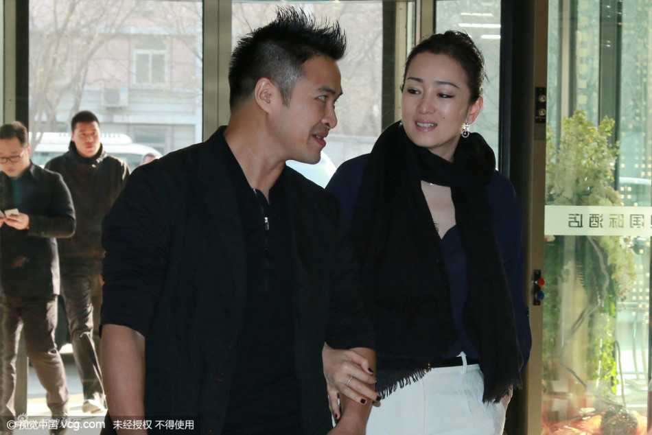 巩俐紧挽粗犷男友人手臂 表情深情举止亲昵