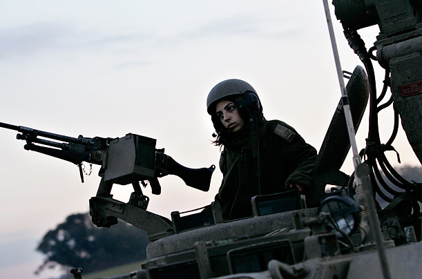 以色列女兵坐在装甲运输车的炮塔口上,一列坦克开进加沙地带准备在