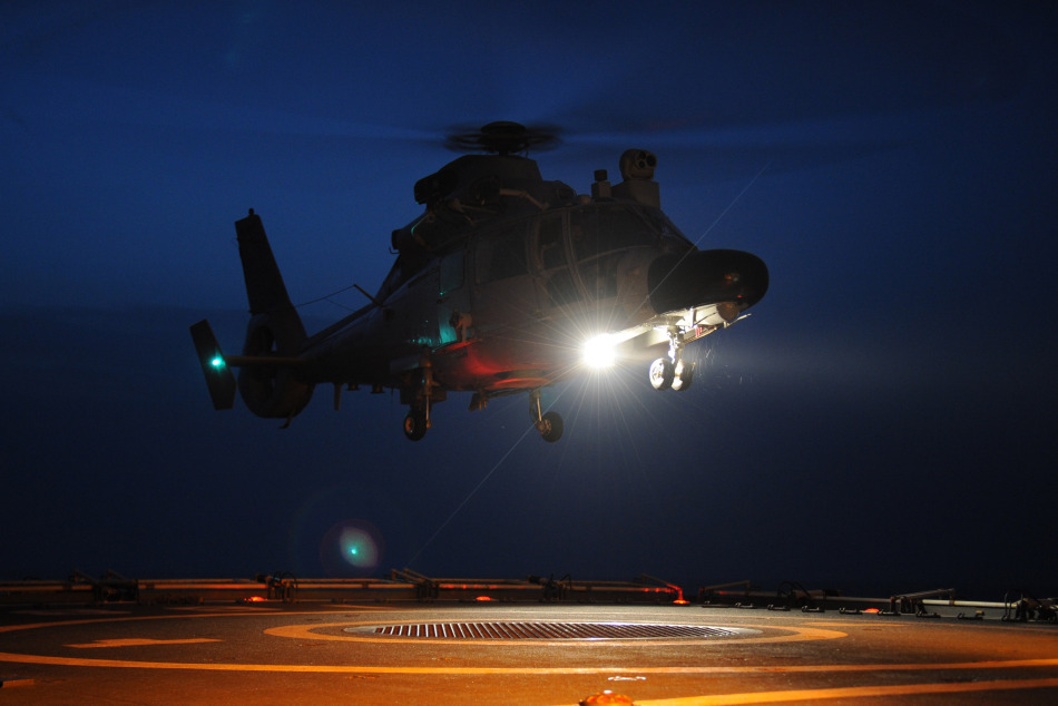 官兵为即将执行夜间着舰训练的直升机设计飞行路线