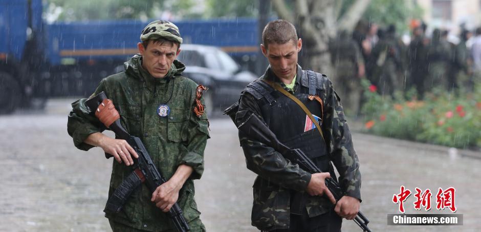 29日,乌克兰顿涅茨克州政府大楼外,两名民间武装人员冒雨巡逻.