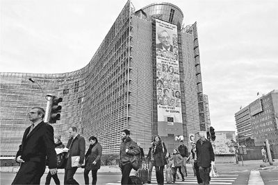 西方民众对选举政治的热情日益降温。图为比利时首都布鲁塞尔，行色匆匆的人们从欧盟委员会大楼上悬挂的新任欧委会成员宣传海报前走过。