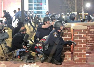 3月12日凌晨，弗格森市警察局外，警察在枪击事件发生后寻找掩体隐蔽。新华社发