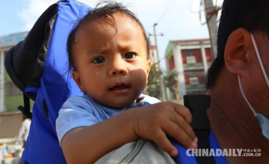 5月12日，在尼泊尔加德满都，一名家长背着孩子转移至安全地带。 据中国地震台网测定，尼泊尔北京时间5月12日15时5分，发生7.5级地震。 新华社发(苏尼尔·夏尔马摄)