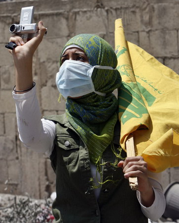 图文:一名女黎巴嫩支持者拍摄轰炸地区受损情景