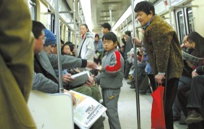 北京地铁1号线，一名妇女领着一个孩子在车厢内行乞。图/CFP