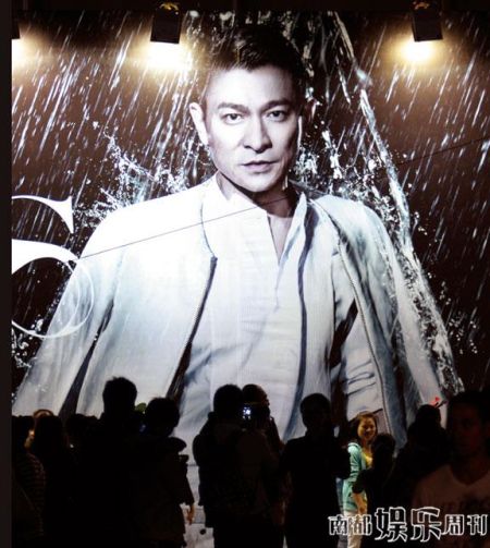 粉丝在刘德华演唱会的巨幅海报下拍照。