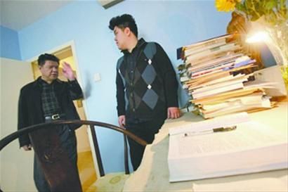 李默然长子李龙吟(左)和孙子李唫在家中的书房，他们仍不愿改动老人生前书桌的模样。 刘汩 摄 