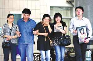 谭静的母亲（中）在亲友搀扶下走出灵堂，悲痛欲绝。