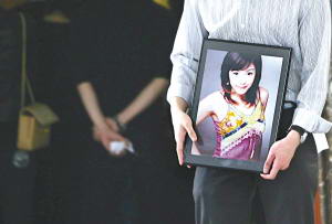 谭静的亲友怀抱谭静的遗照走出灵堂。