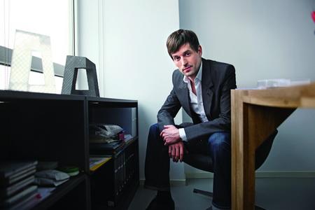 奥雷·舍人在自己的Bro Ole Scheeren建筑事务所内，旁边摆放着几个不同材质的央视大楼的模型