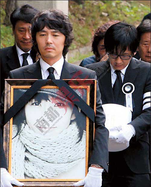 崔真实的弟弟崔真英手捧姐姐遗像为她送行。