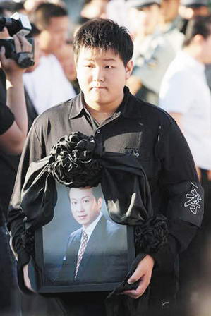 罗京的儿子罗疏桐抱着父亲的遗像