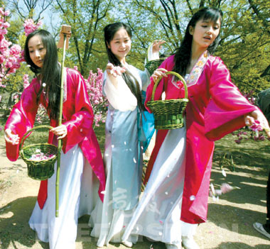 穿上古装的“黛玉”手挽装满桃花瓣的花篮，在桃树下“葬花”