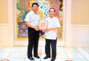 天津歌舞剧院院长高久林向中国驻新加坡大使馆文化参赞陈江送上“天津歌舞剧院50年纪念画册”