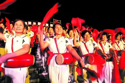 在台下，群众文艺团体打起腰鼓来助兴