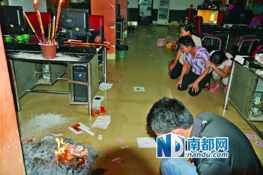 死者亲属在网吧内电脑桌旁烧香磕头进行祭奠。