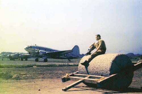 威廉·迪柏坐在机场工地的碾子上，正望着起降的飞机。(艾伦·拉森摄)