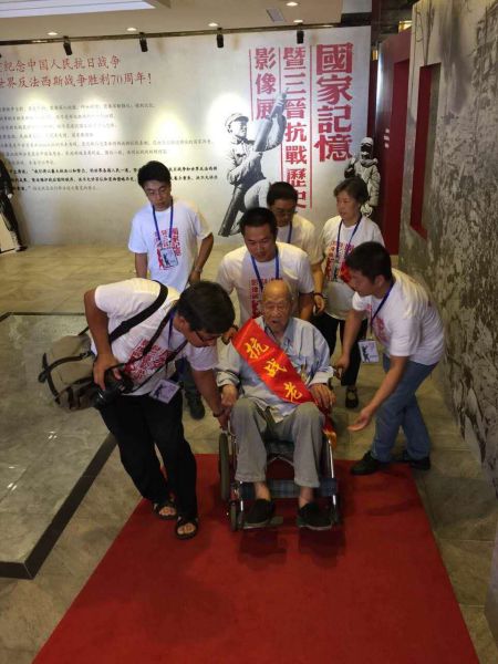 志愿者为抗战老兵推轮椅