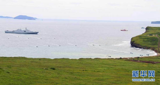 图为14辆两栖装甲从长白山舰庞大的登陆舱内鱼贯而出，划开浪花向滩头冲击