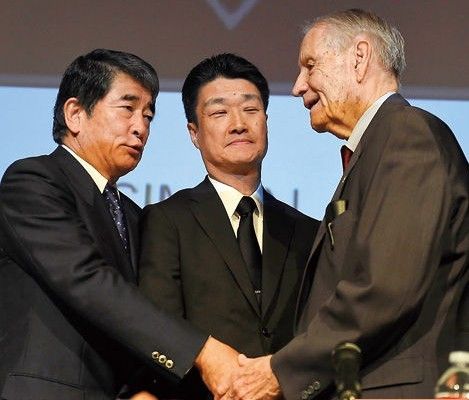     7月19日,在美国洛杉矶,美军战俘劳工代表詹姆斯·墨菲(右)与日本三菱综合材料公司高管木村光及外部董事冈本行夫握手。