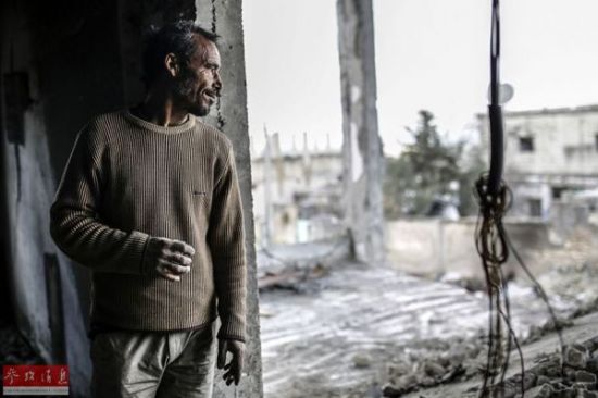 　　资料图：在叙利亚艾因阿拉伯，一名库尔德人查看损毁的房屋。